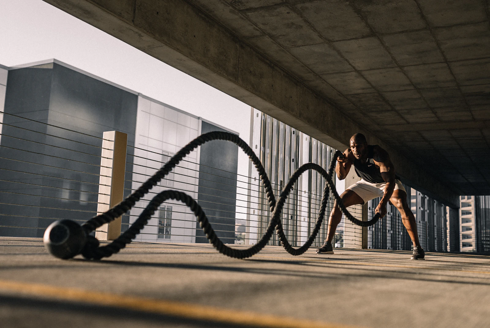 Sportif travaillant avec des cordes ondulatoires (battle ropes) sous un passage couvert
